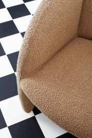 Modernist Paulin armchair reupholstered in latte bouclé against a black and white chequered floor. 