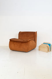 Modular vintage brown armchair and beige magazine holder on a white floor with white wall background