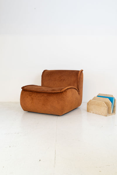 Modular vintage brown armchair and beige magazine holder on a white floor with white wall background