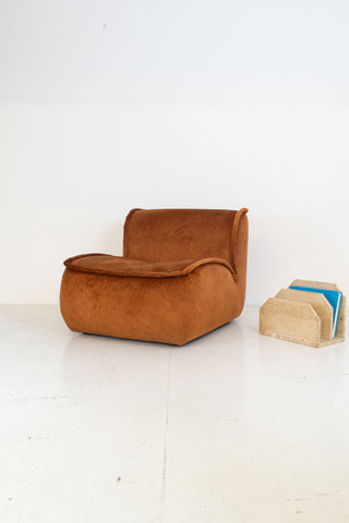 Modular vintage brown armchair and beige magazine holder on a white floor with white wall background
