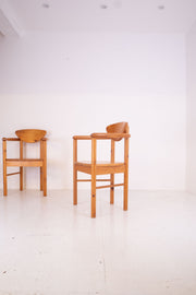 Two vintage pine carver chairs  on a white floor and white wall