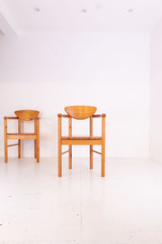 Two wooden chairs on a white floor with a white wall background