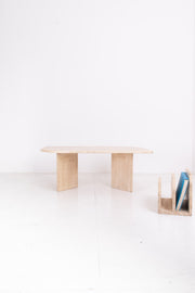 Minimalist travertine table with a travertine magazine rack on a white background