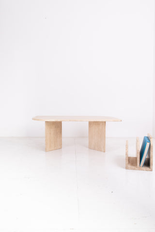 Minimalist travertine table with a travertine magazine rack on a white background