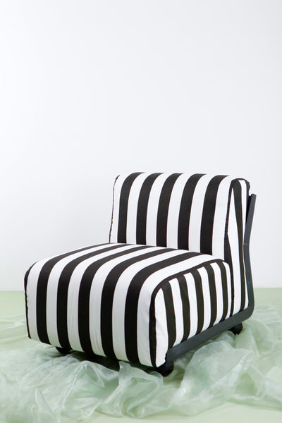 Black and white striped vintage Mario Bellini Amanta 24 armchair against white background with green floor.