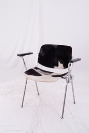 Vintage Castelli metal stacking chair with cowhide seat against white drapes