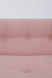 Close up of pink boucle upholstery on retro Italian accent chair against white background