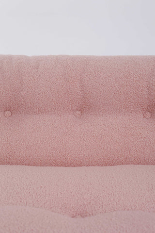 Close up of pink boucle upholstery on retro Italian accent chair against white background