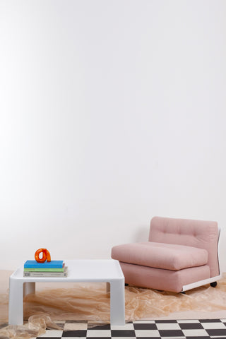 Pink boucle vintage B&B Italia armchair beside white Amanta coffee table against white background and chequered floor. 