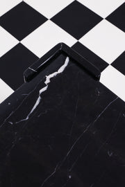 Close up of detailing on vintage Italian black and white marble side table against a chequered backdrop.