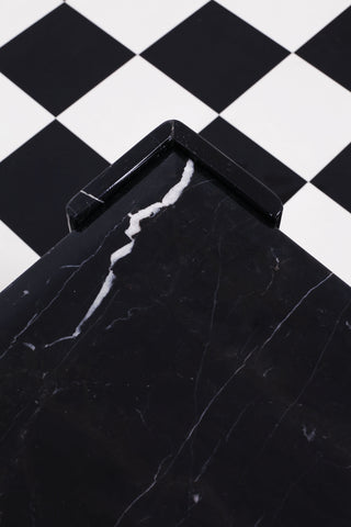 Close up of detailing on vintage Italian black and white marble side table against a chequered backdrop.