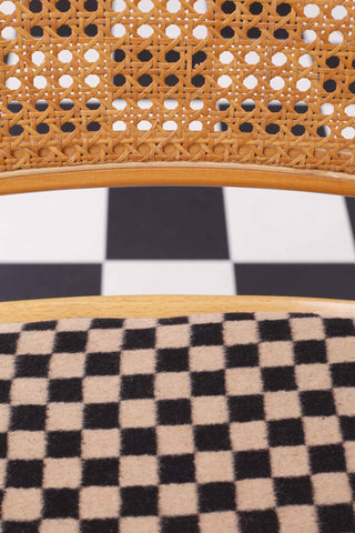 Close up of vintage upholstered Cesca chair with cane seat back against a chequered floor 