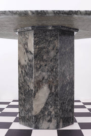 Detail shot of central column on vintage grey marble dining table against a white backdrop and a chequered floor. 