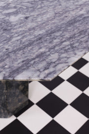 Detailed shot of corner of tabletop of vintage grey marble dining table against chequered floor