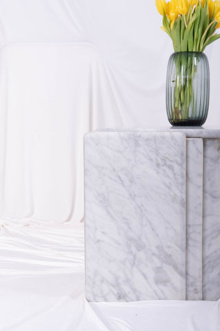 Close-up of the leg of a marble coffee table in front of white drapes. 