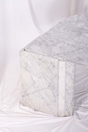 Detail shot of the leg of Carrara marble coffee table against white drapes