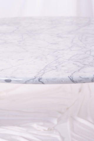 Shot of signs of wear on large white marble coffee table. Image taken against white drapes.