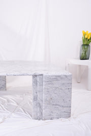 Close-up shot of leg of large white marble coffee table in front of Kartell with daffodils on.