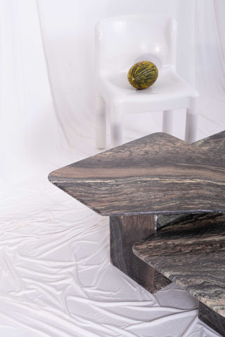 Vintage dark marbled coffee table with white plastic chair in the background
