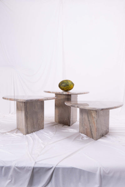Set of three marble nesting coffee tables with melon and white draped fabric in the background