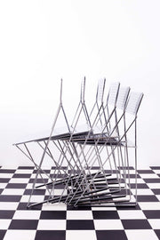 Set of X-Line stacking chairs against a white background and a chequered floor. 
