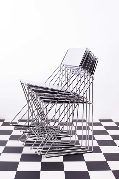 Set of 6 vintage stacking X-Line chairs against a white backdrop and a chequered floor.